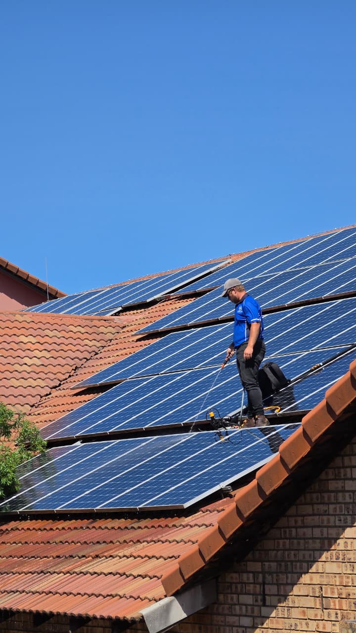 RobCon Electrical technician cleaning a large residential solar array in Gauteng