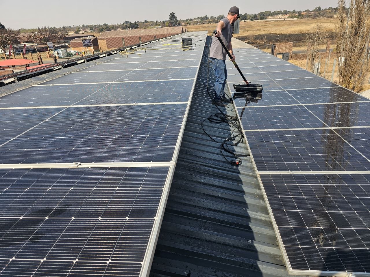 RobCon Electrical crew cleaning a long commercial warehouse solar array in Gauteng